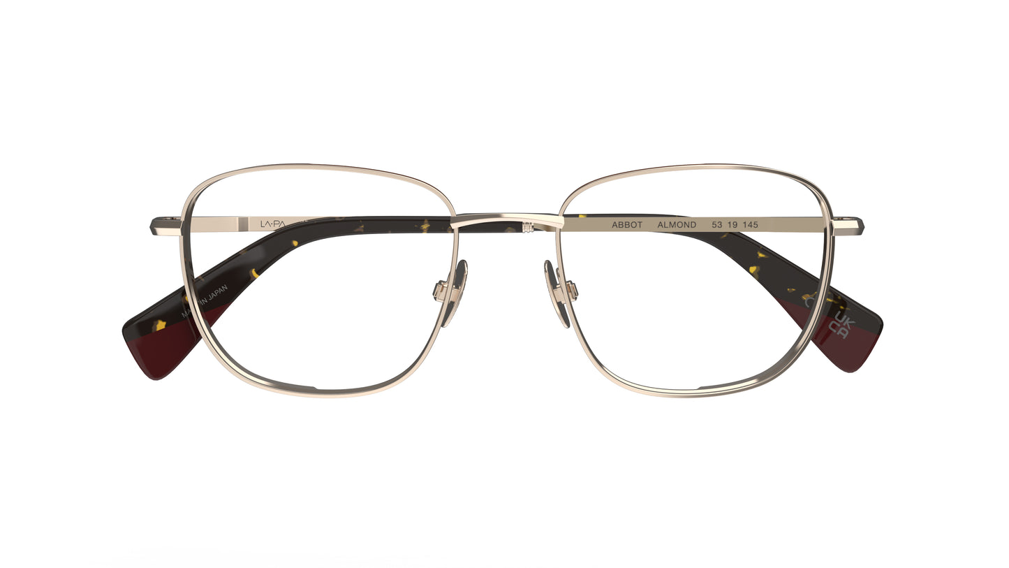 A pair of soft square titanium eyeglass frames with almond-toned rims and nosepads and tortoiseshell acetate temple tips, shown against a plain white background.