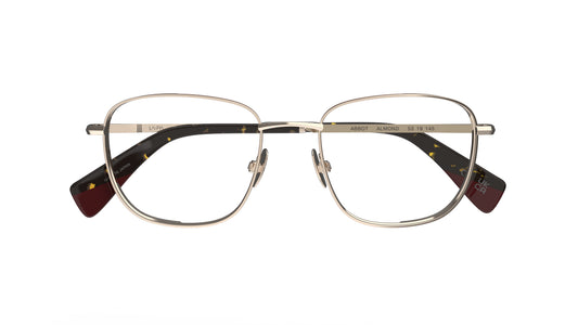 A pair of soft square titanium eyeglass frames with almond-toned rims and nosepads and tortoiseshell acetate temple tips, shown against a plain white background.