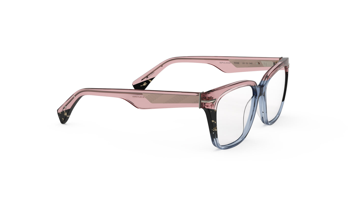 A pair of cat-eye oversized square eyeglasses featuring a translucent pink acetate frame that transitions into a blue gradient at the bottom, with tortoiseshell accents. Geometric patterned wire cores, shown on a plain white background.